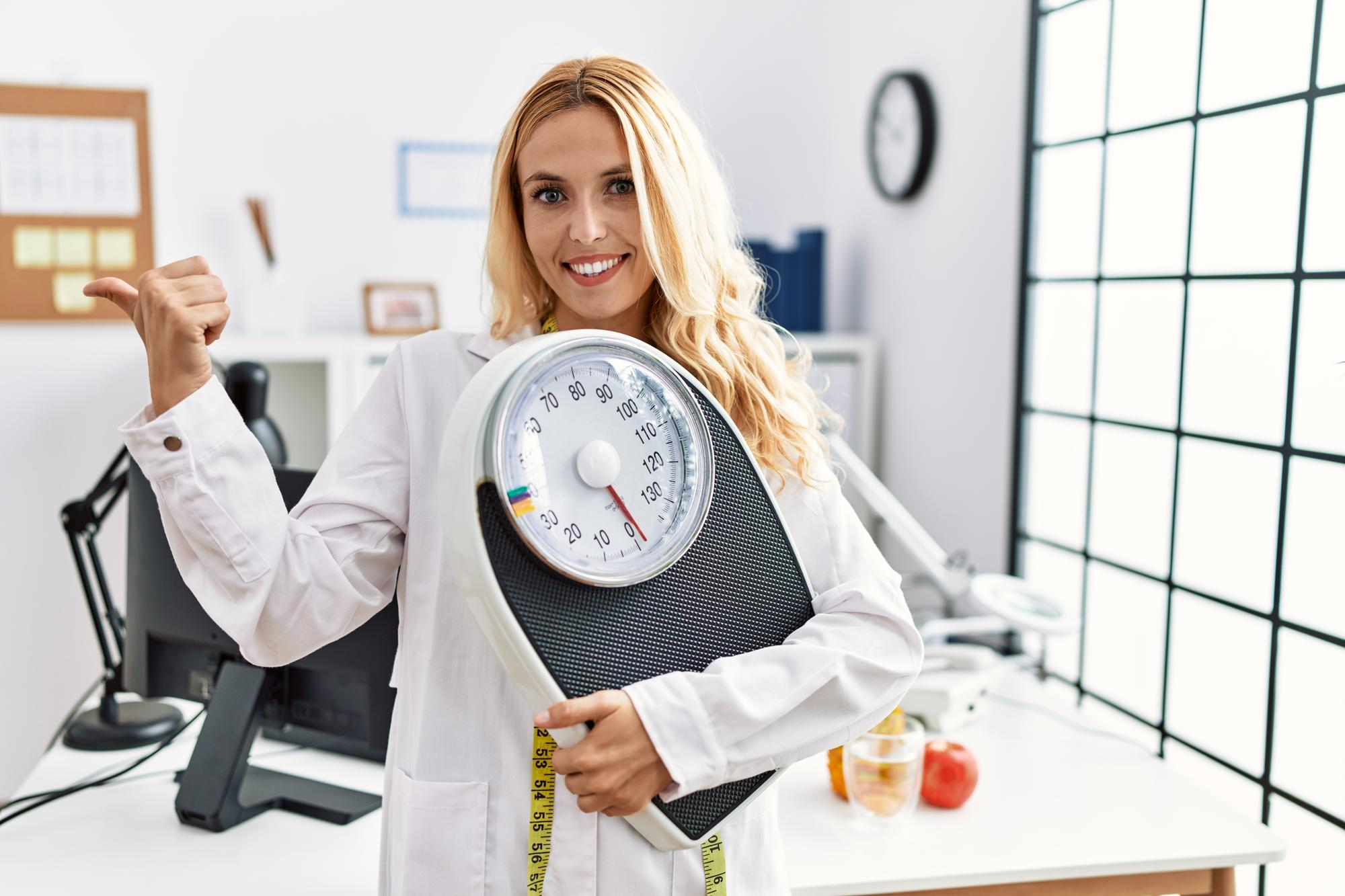 Médica sorridente segurando uma balança em consultório, representando o uso de Ozempic para perda de peso.