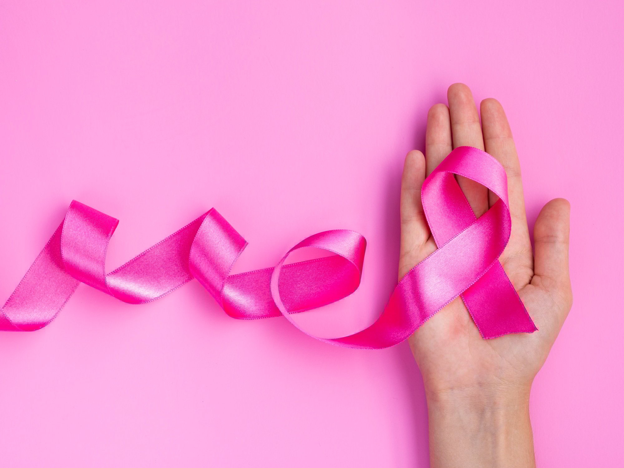 Pessoa segurando um laço rosa, símbolo da conscientização e prevenção do câncer de mama.