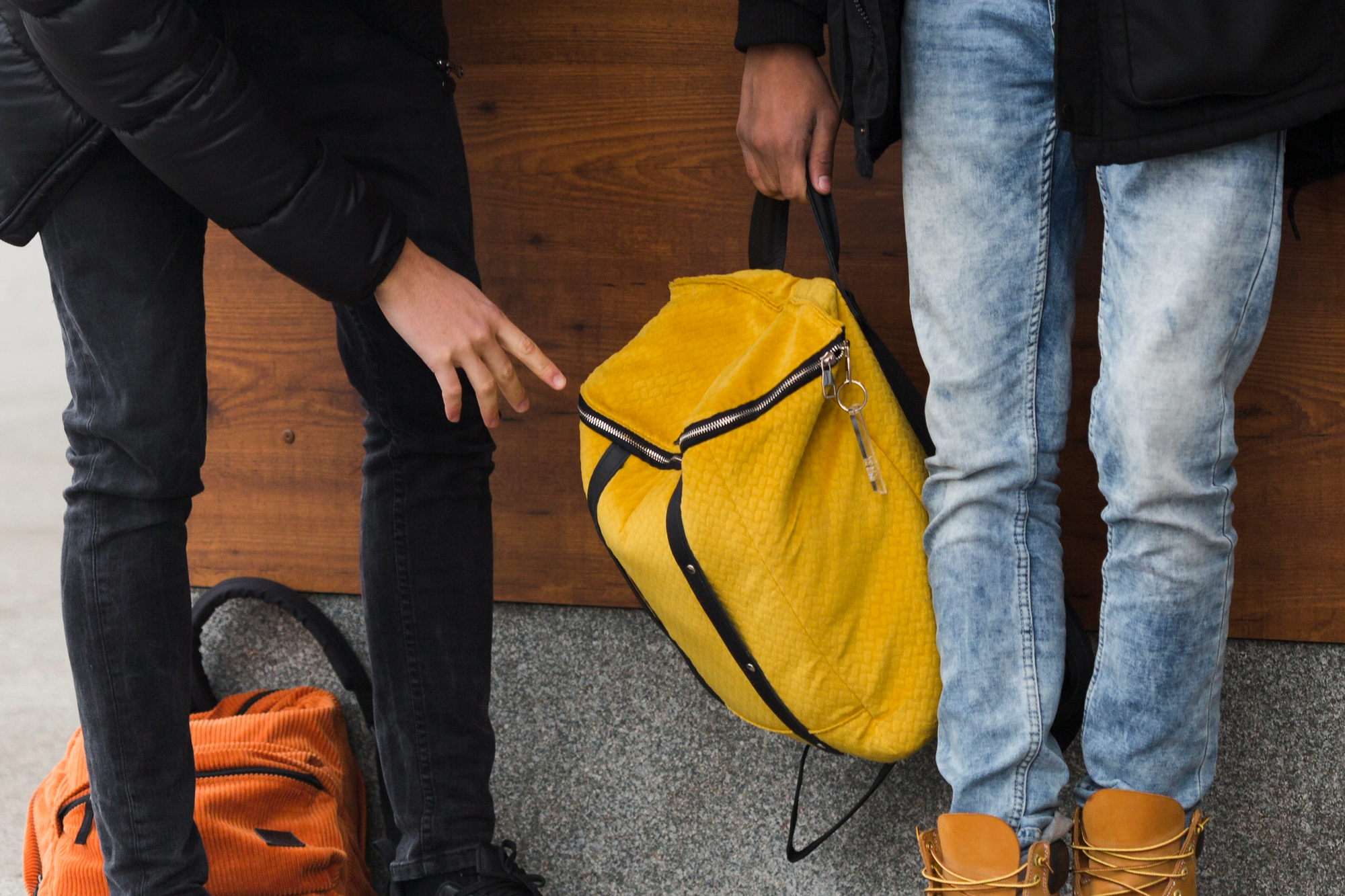 Dois jovens em pé segurando mochilas, ilustrando a importância de carregar peso corretamente para não prejudicar a coluna. 
