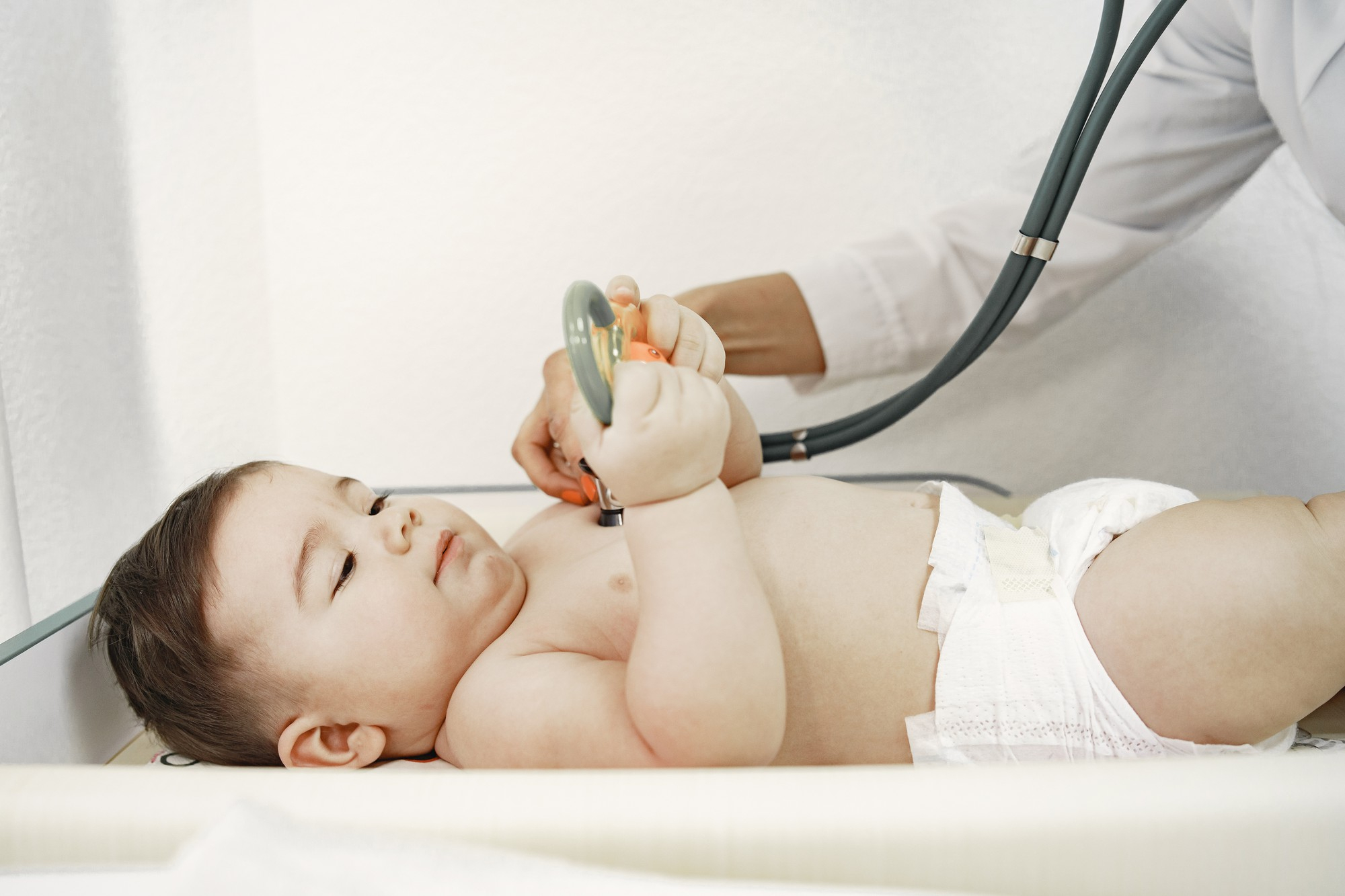 Bebê em consulta médica, sendo examinado pelo pediatra, avaliação importante para diagnóstico precoce de criptorquidia.