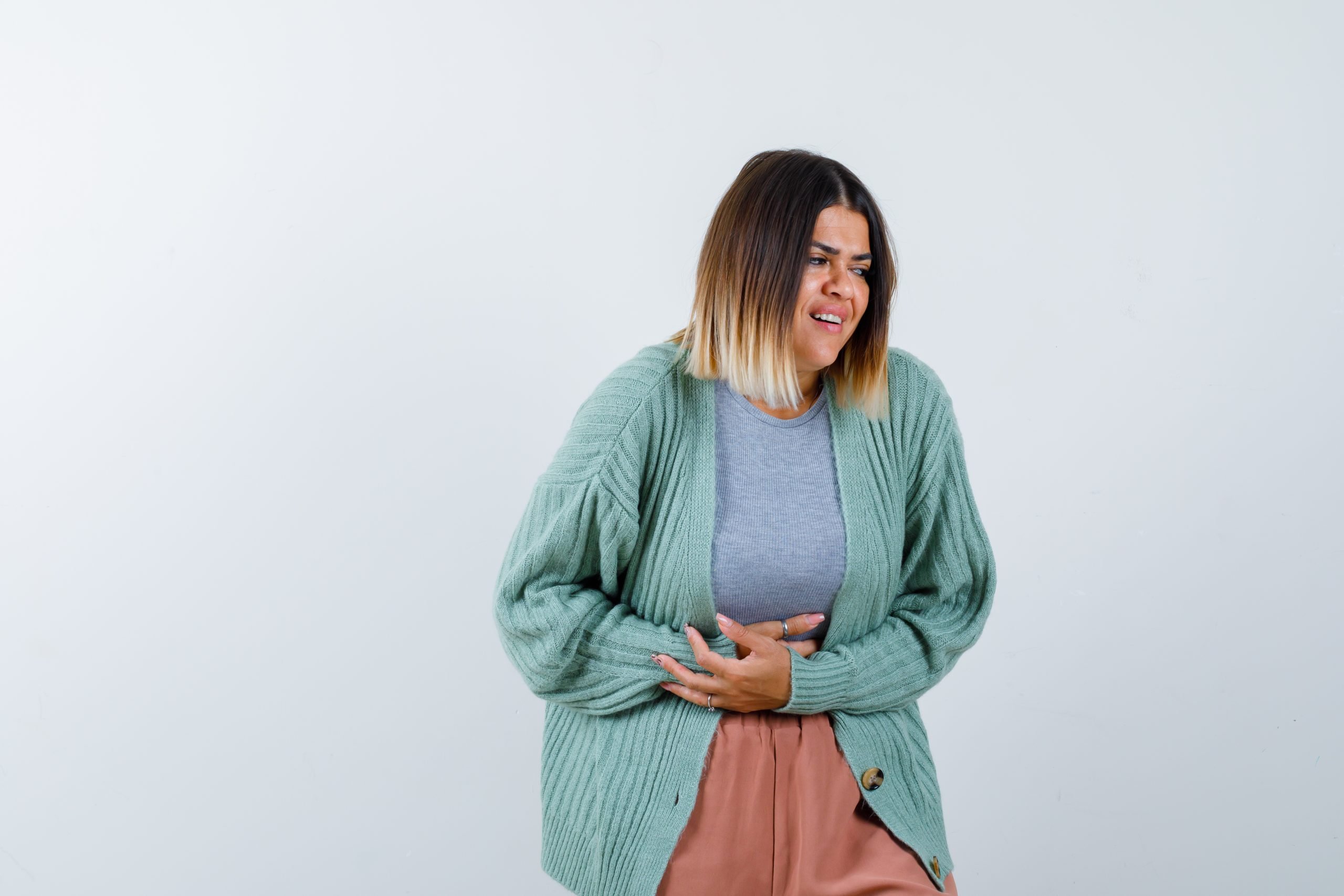 Mulher coloca mão na barriga em sinal de dor abdominal