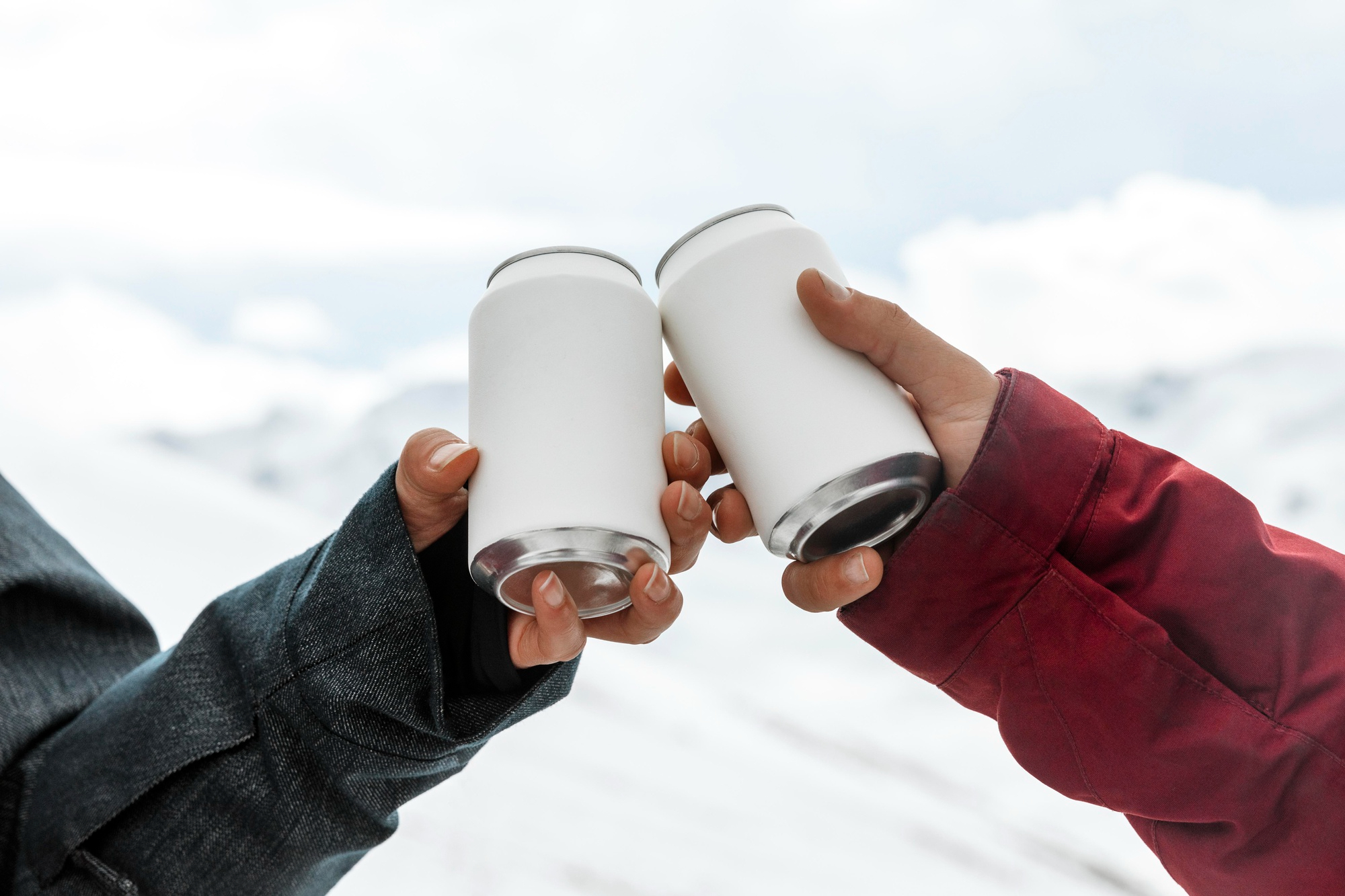 Duas pessoas brindando com latas brancas de energéticos em ambiente ao ar livre e se questionando se energético faz mal