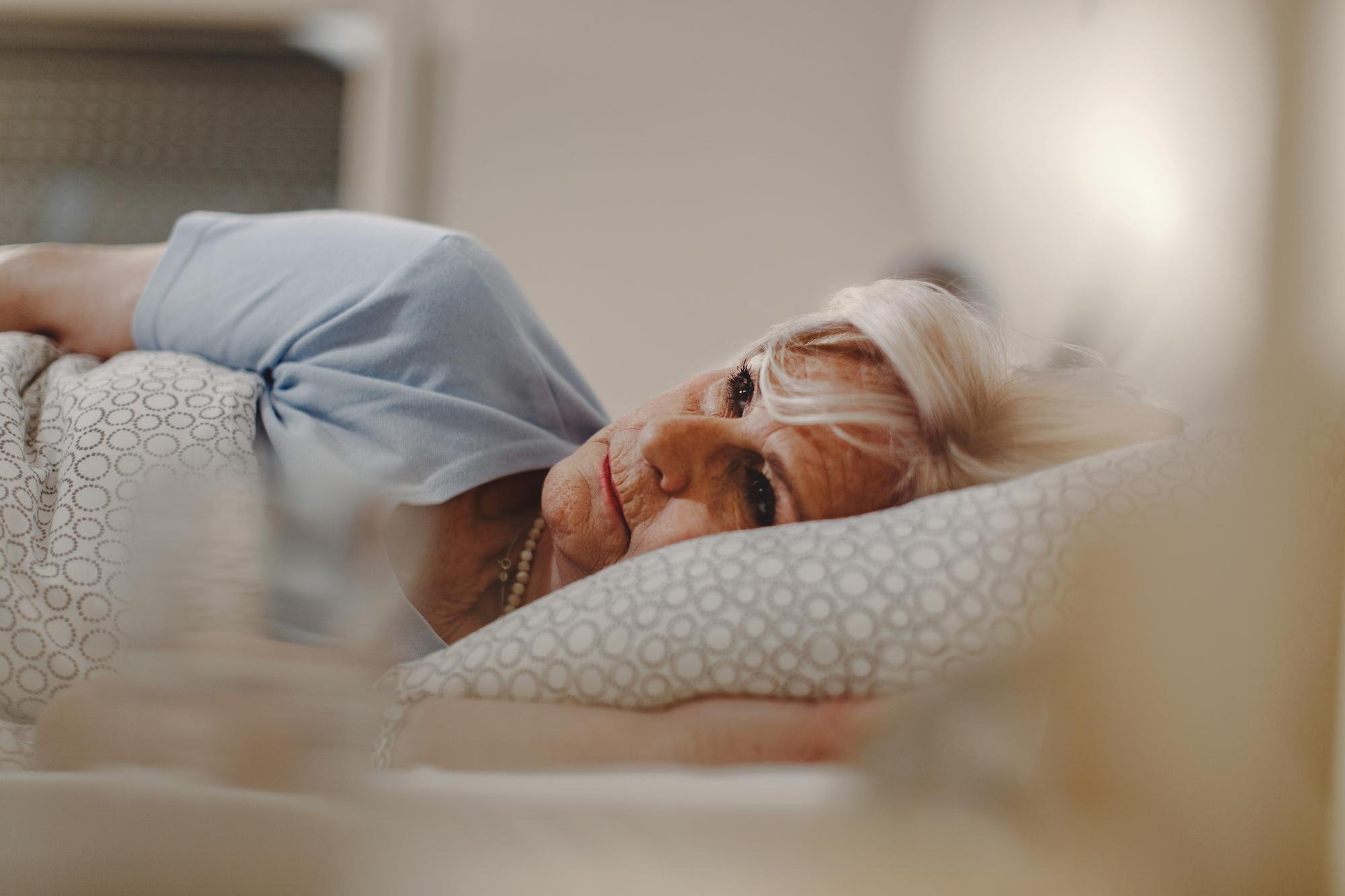 Mulher deitada na cama com dificuldade para dormir, representando insônia na menopausa.