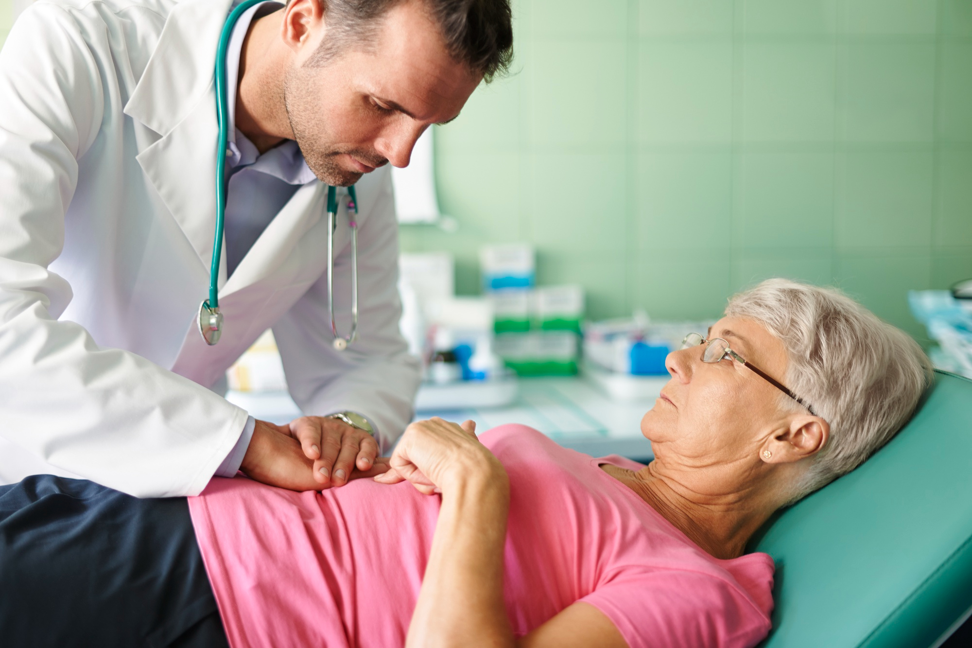 Médico examina abdômen de mulher idosa com suspeita de pancreatite aguda