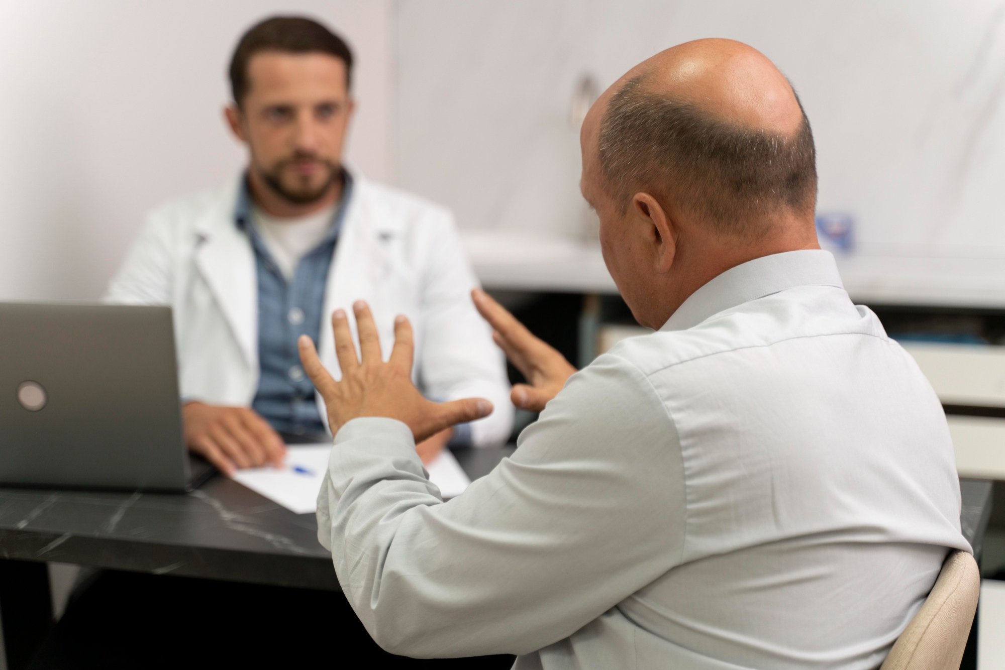 Homem calvo com sintomas de próstata aumentada conversa com urologista para entender o melhor tratamento.