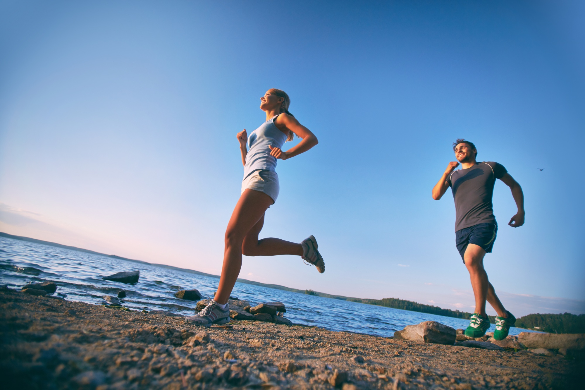 Homem e mulher fazem corrida na praia como forma de manter o exercício nas férias