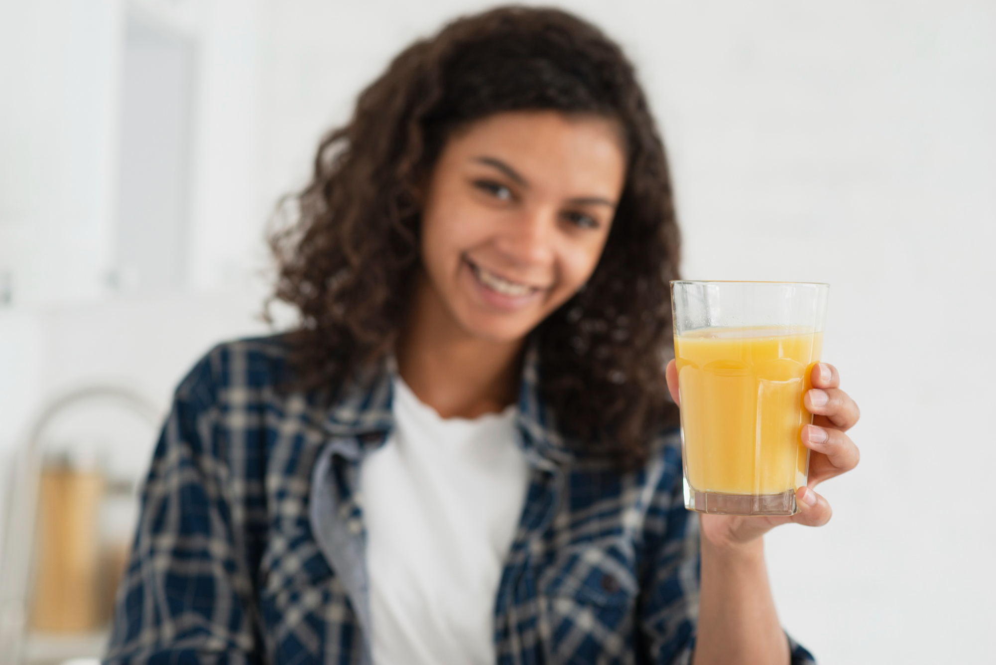 Mulher segura copo de suco de maracujá com semblante calmo e feliz
