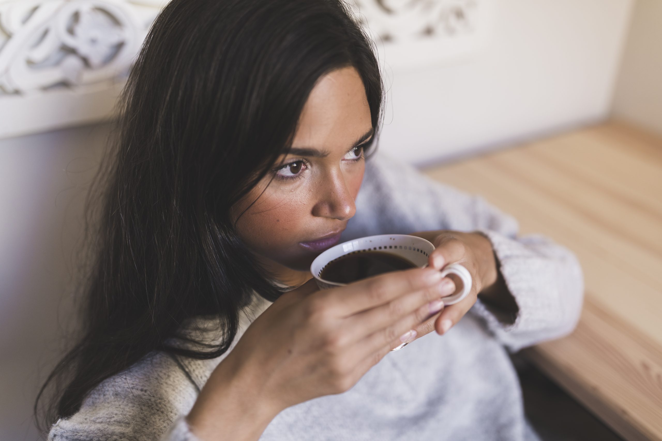 Mulher tomando uma xícara de café preto pela manhã.