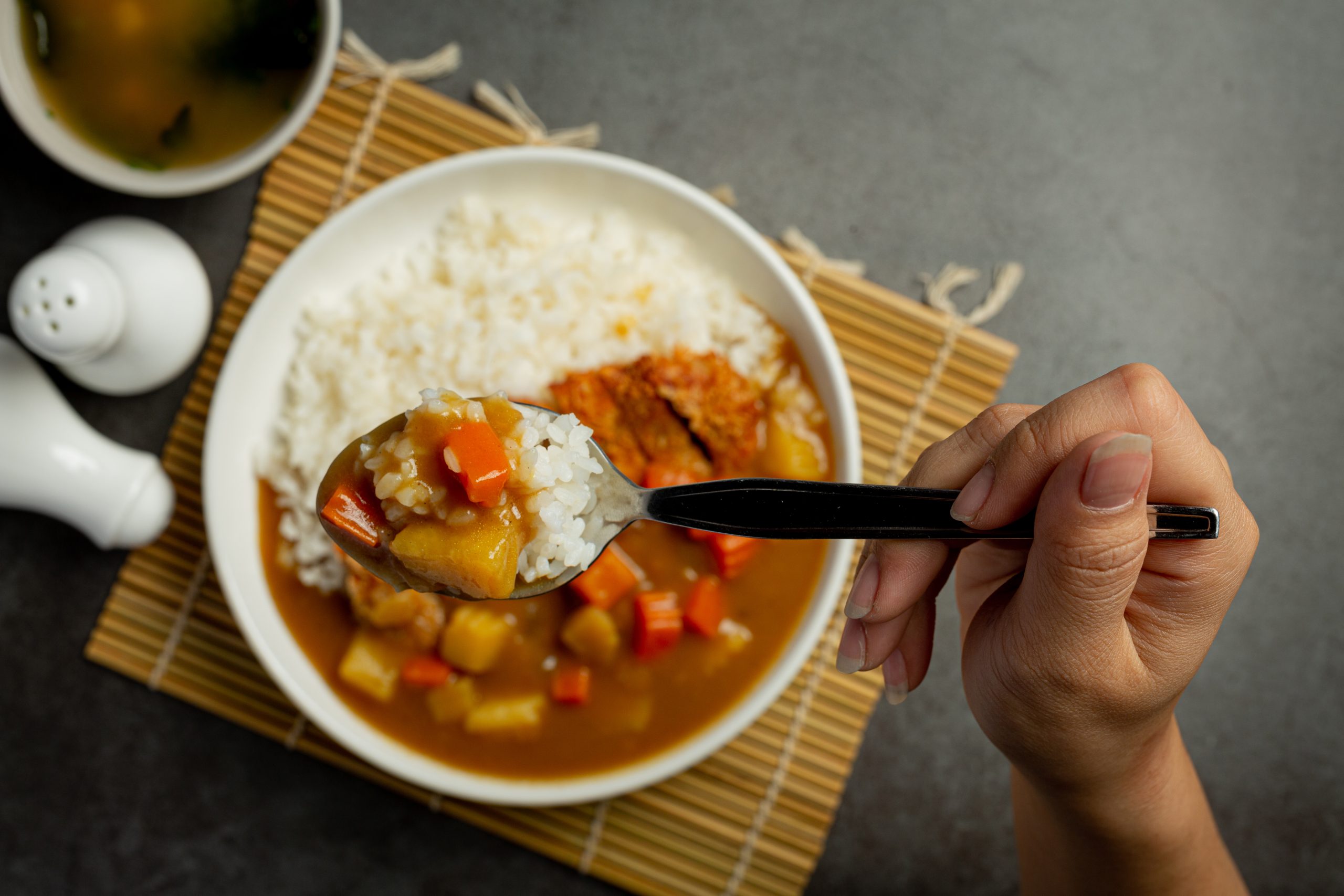 Pessoa segurando colher com arroz e legumes sobre prato de comida, representando as porções recomendadas pela pirâmide alimentar.
