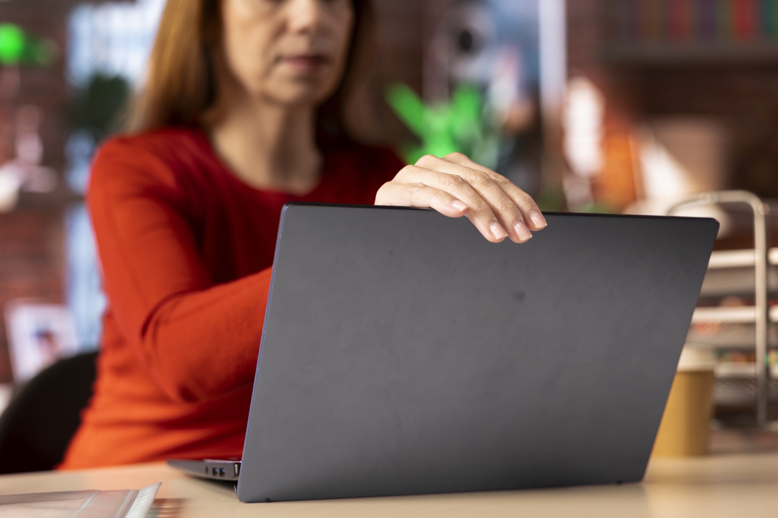 Mulher fechando o notebook ao fim do expediente, representando o ritual de encerrar o trabalho e ajudar o cérebro a sair do modo trabalho para iniciar o momento de descanso.