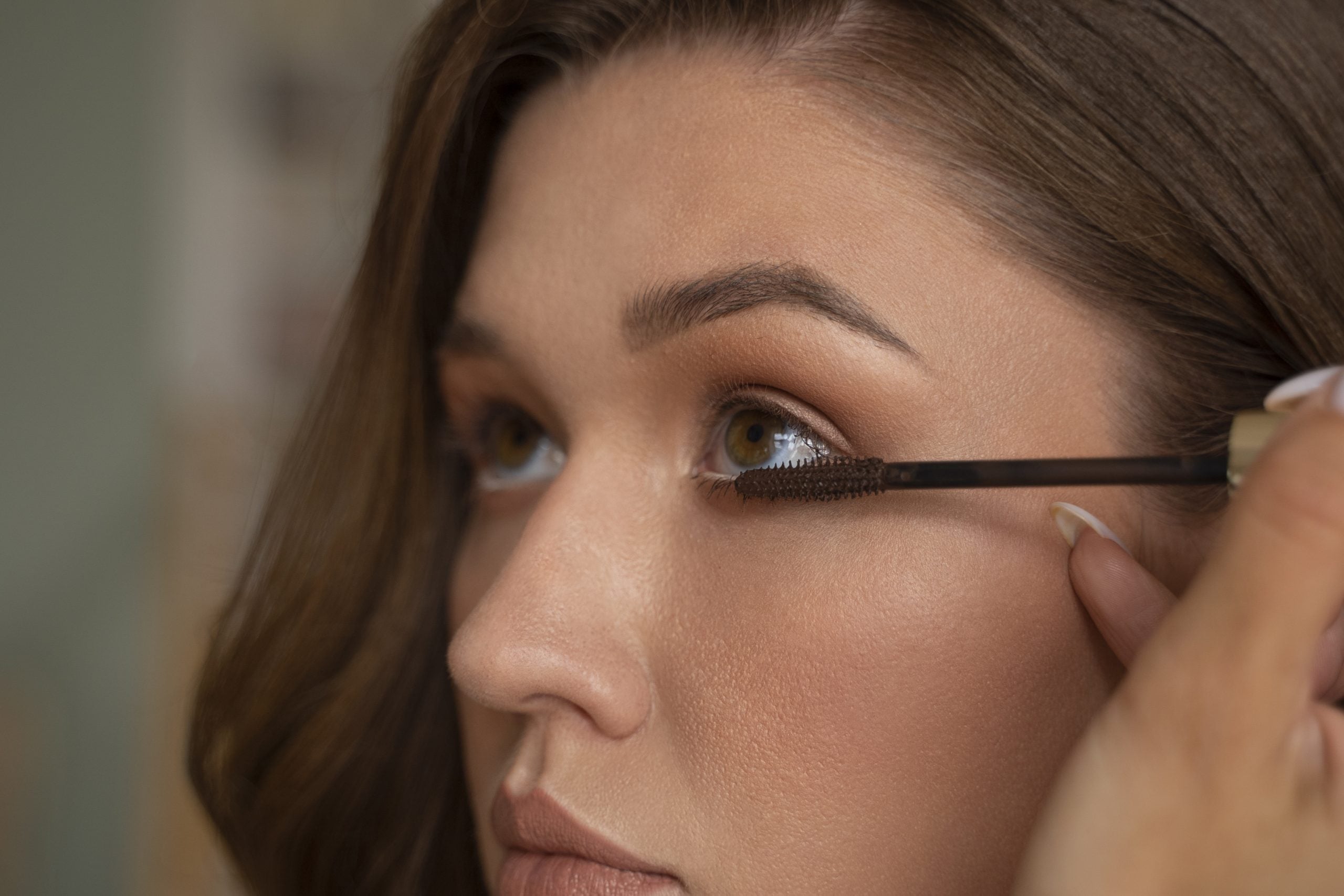 Mulher aplica máscara de cílios nos olhos, maquiagem que pode aumentar o risco de irritação ou conjuntivite quando usada fora da validade ou contaminada.