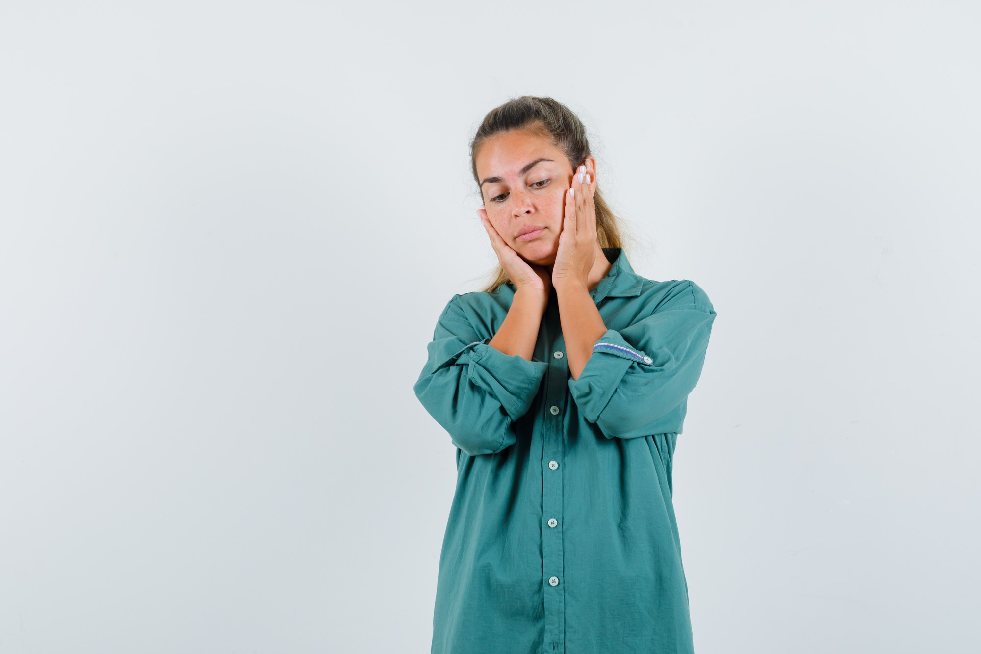 Mulher com dor na região da mandíbula e da têmpora enquanto toca o rosto.