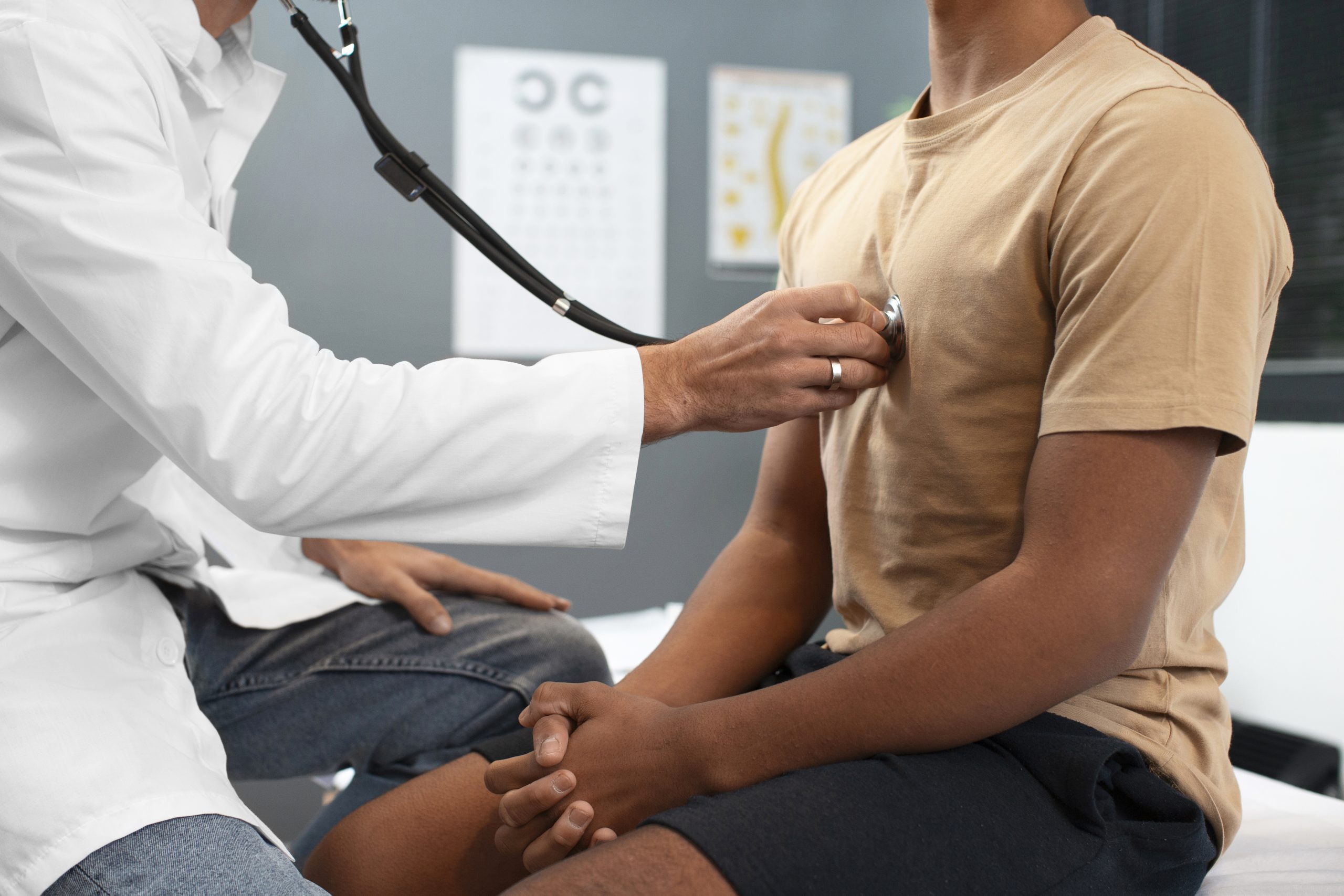 Cardiologista realiza exame com estetoscópio no peito de um paciente sentado em um consultório durante uma consulta de check-up cardíaco.