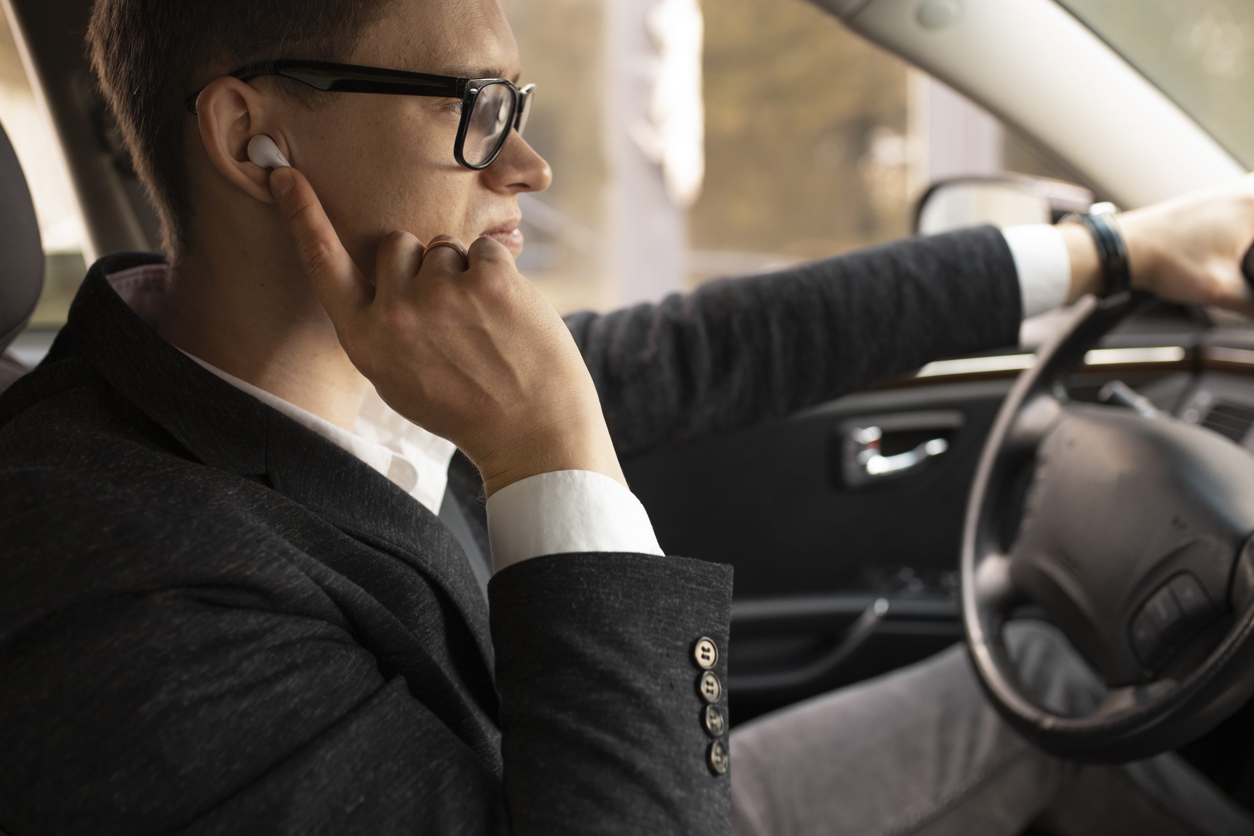 Homem dirige um carro enquanto toca o ouvido com o dedo, representando a sensação de ouvido tampado durante a descida de uma serra.
