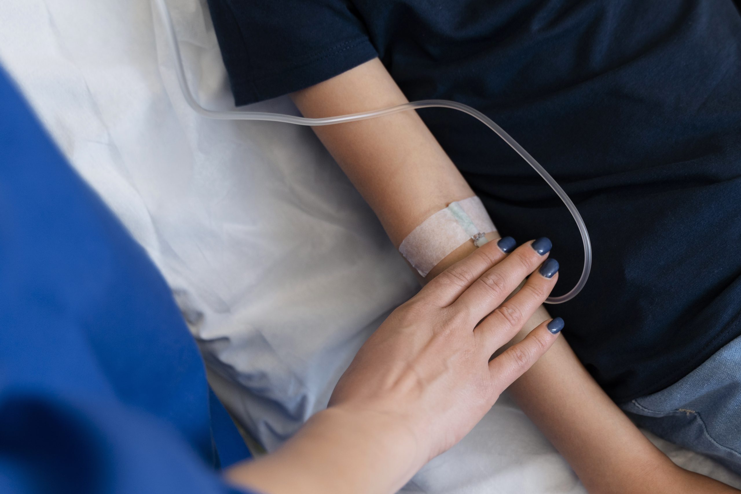 Paciente com acesso intravenoso no braço recebe medicação durante uma sessão de tratamento contra o câncer.