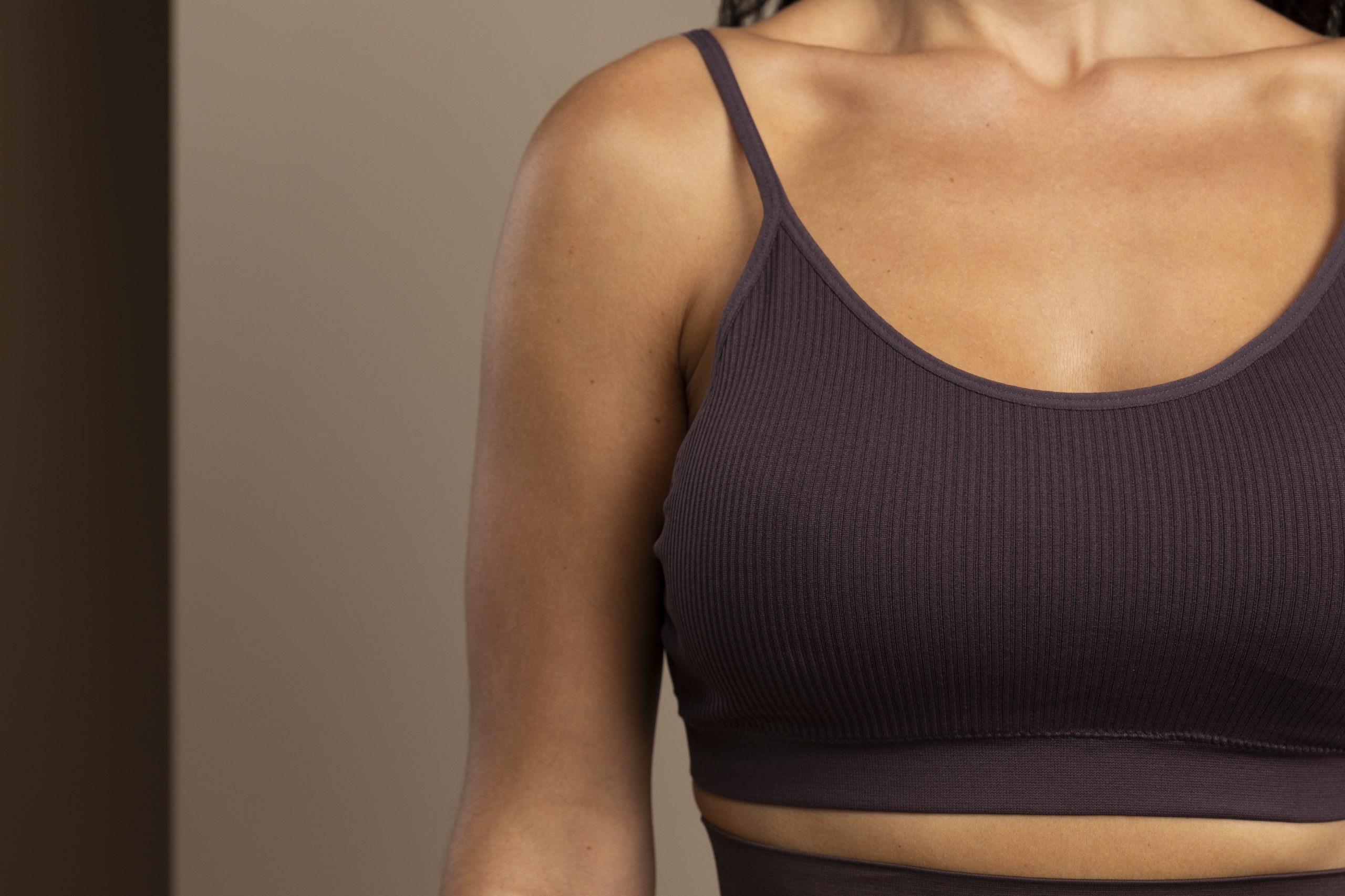 Mulher usando top escuro, com enquadramento do colo e das mamas, em imagem ilustrativa sobre mastectomia preventiva.