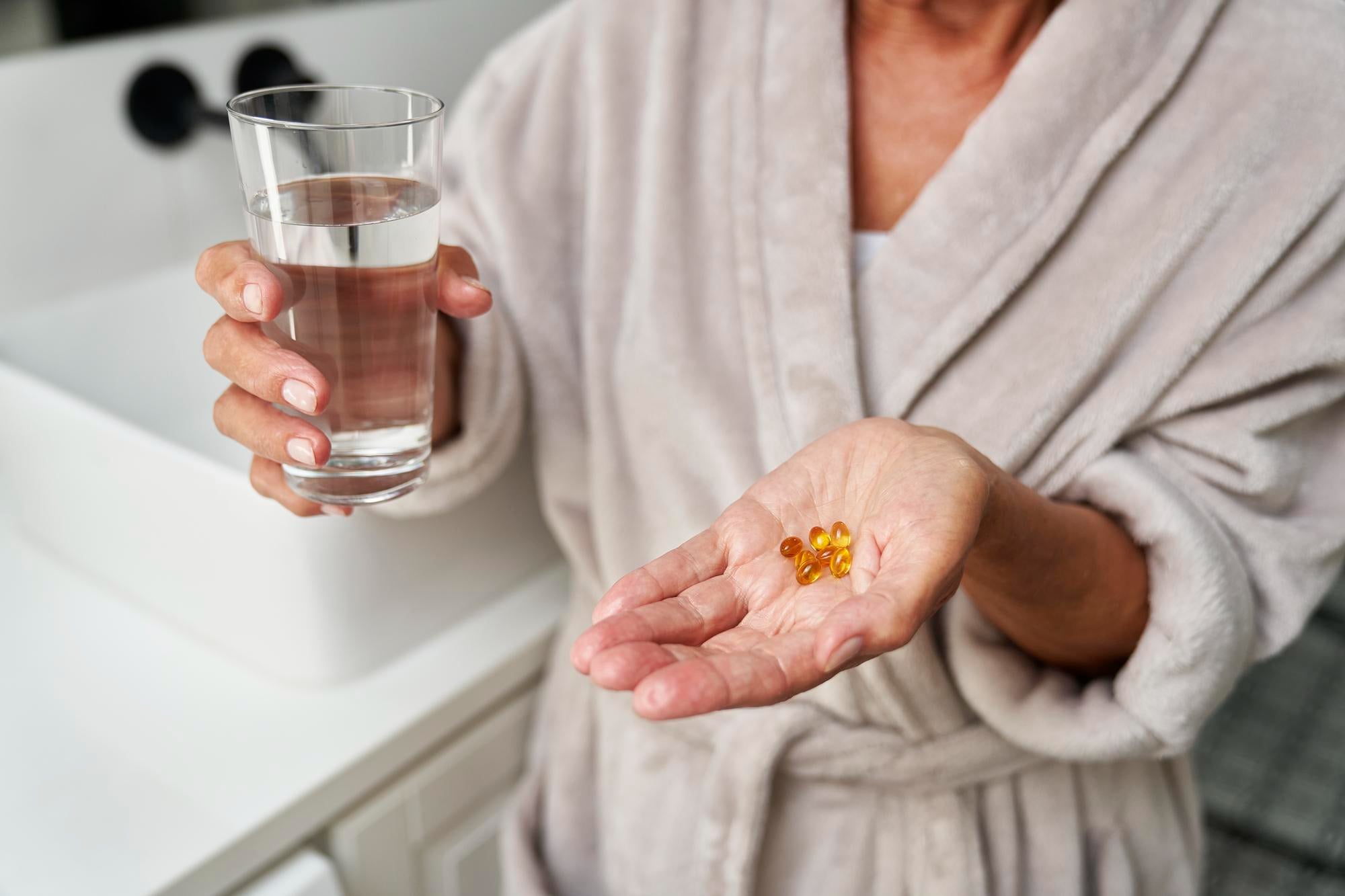 Pessoa tomando suplementos alimentares que talvez precisem ser suspensos antes de uma cirurgia.